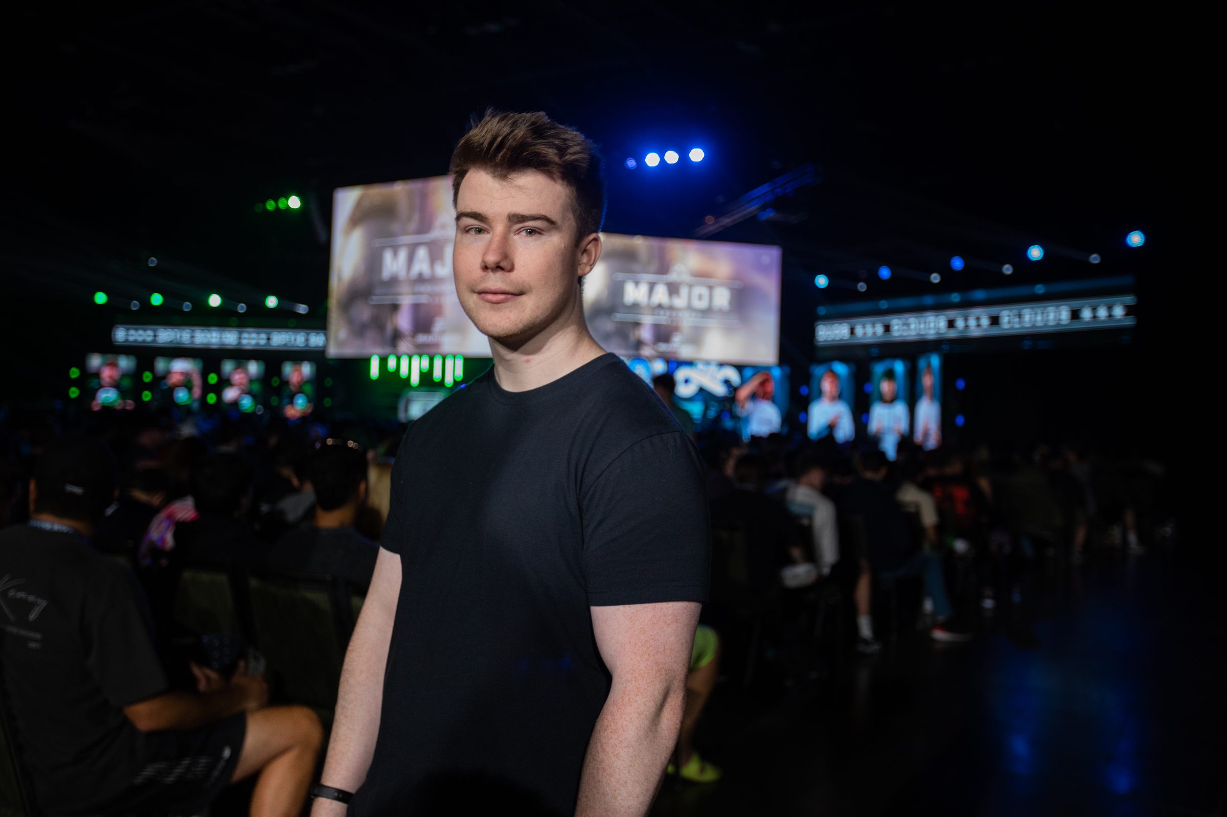 Riley Hastings standing in the crowd at a Halo Championship Series Major, stage screens lit behind him.
